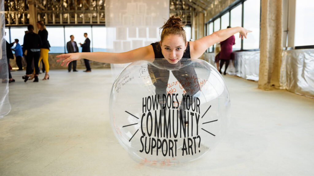 interpretative dancer leaning on clear ball with a message on it