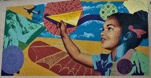 Colorful mural depicting a child launching a paper airplane against a vibrant artistic background.
